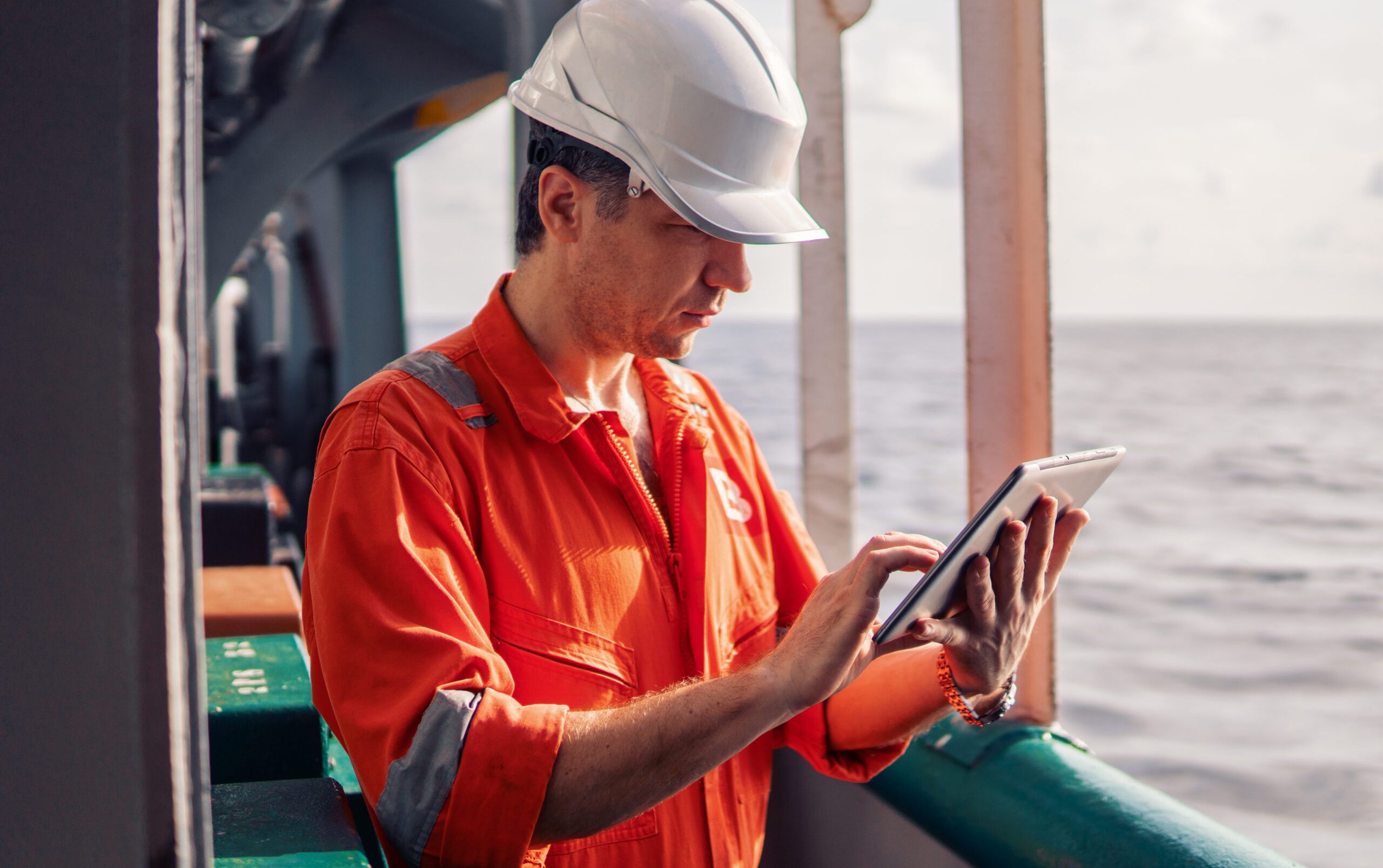 Marine chief officer or captain on deck of vessel or ship watching digital tablet. Internet and home connection at sea.